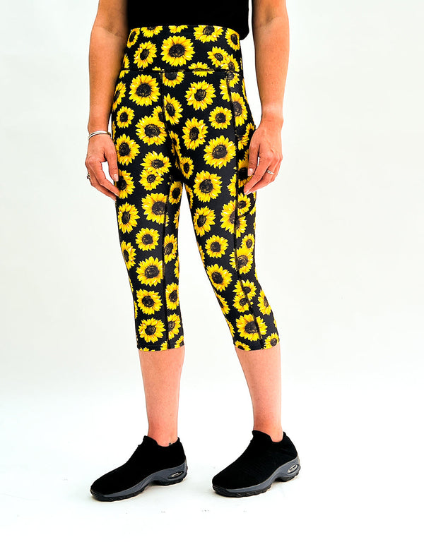 Black gym leggings with vibrant yellow sunflower print and deep side pockets worn with black shoes