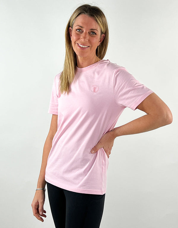 Woman wearing baby pink casual llama t-shirt with embroidered logo and black leggings.