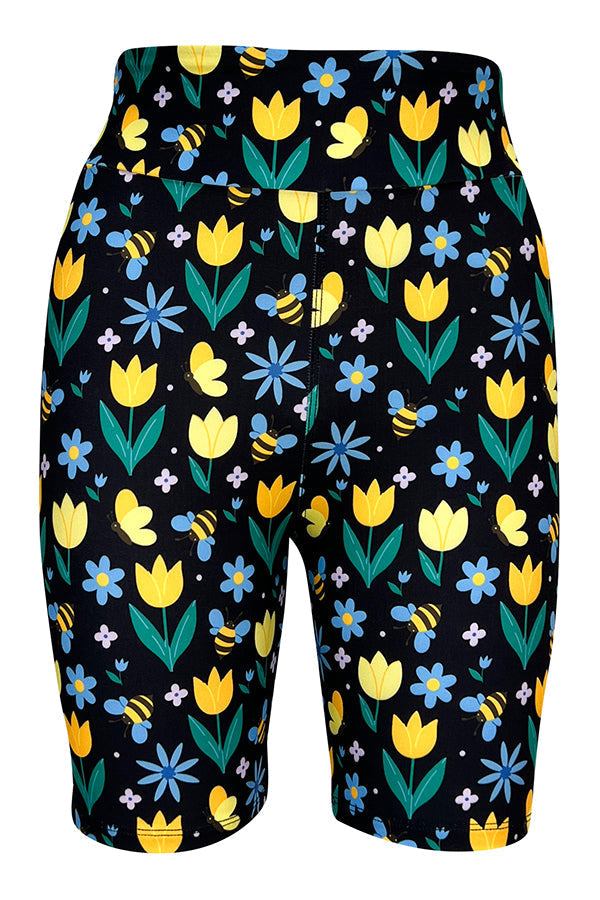 Black tight shorts with colorful tulip, blue flower, bumblebee, and butterfly print, made from stretchy fabric with a secure elastic waistband.